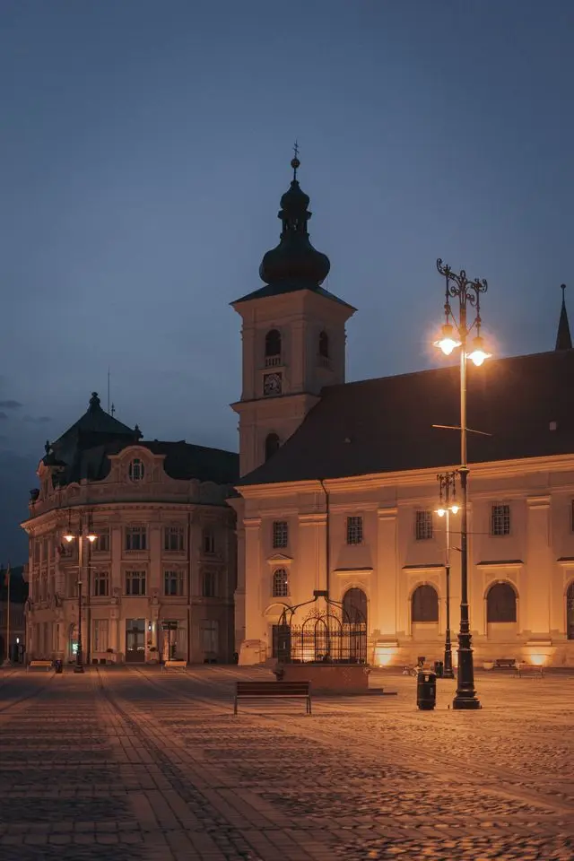 Illuminated historic church and buildings in Sibiu, Romania, at dusk