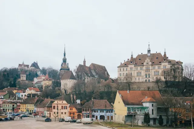 Panoramic view of Sighișoara with historic buildings, church towers, and surrounding wooded hills