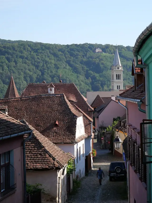 Traditional tiled rooftops, colorful houses, and a church tower overlooking Sighișoara, Romania