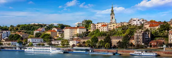 Belgrade Serbia cityscape with historic buildings, riverfront promenade and boats under a blue sky