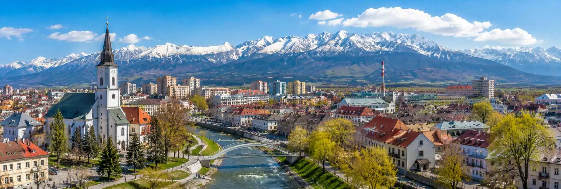 Poprad, Slovakia, with its historic church, city rooftops, river and snow-capped High Tatras mountains.