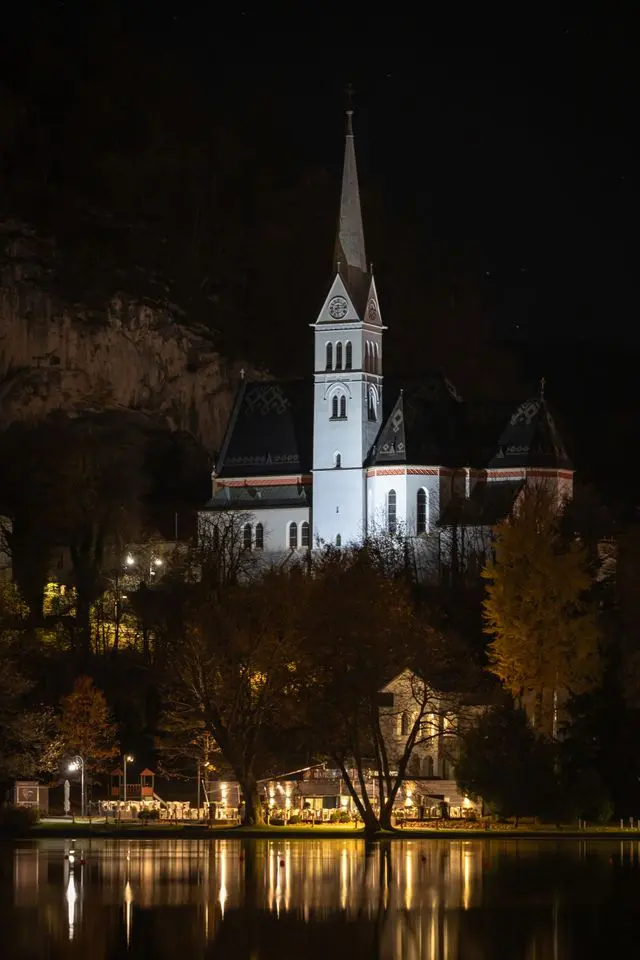 Bled Island church illuminated at night beside Lake Bled in Slovenia