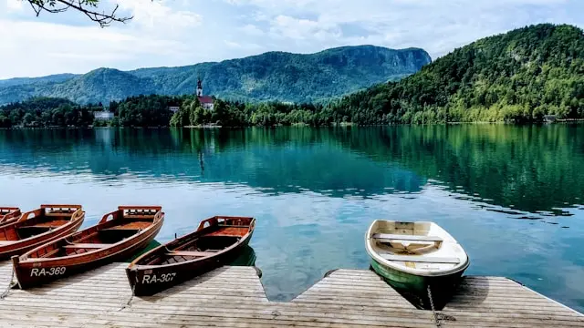 Traditional boats on Lake Bled with Bled Island and forested hills in Slovenia