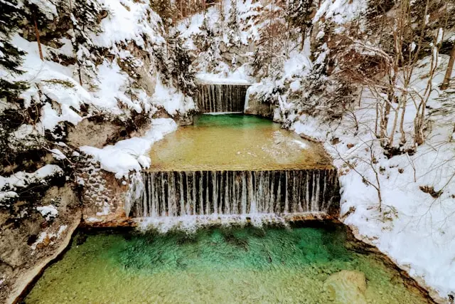 Turquoise waterfall and stream surrounded by snow in Kranjska Gora, Slovenia