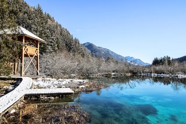 Turquoise Lake Jasna surrounded by snowy mountains and forest in Kranjska Gora