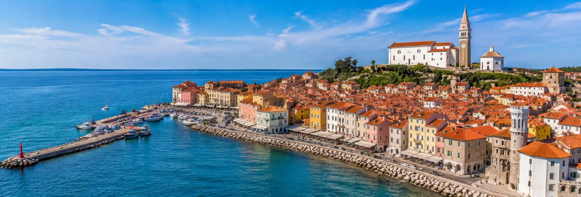 Piran waterfront with colorful Venetian buildings, Adriatic Sea and St. George's Church in Slovenia.