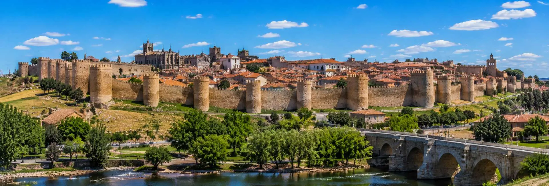 Ávila, Spain, featuring its medieval stone walls, historic old town, and cathedral under a clear blue sky
