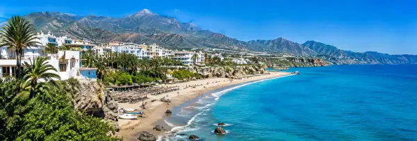 Costa del Sol coastline with turquoise sea, sandy beach, palm trees and Andalusian mountains