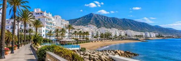 Estepona, Spain, with whitewashed buildings, palm-lined promenade, sandy beach, and Mediterranean Sea