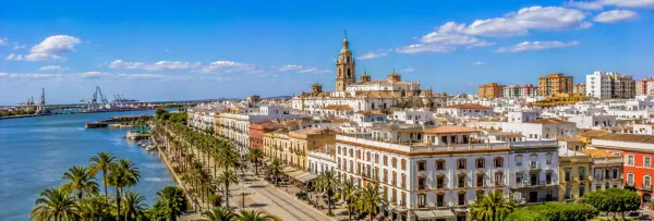 Panoramic view of Huelva, Spain, with the Odiel River, palm-lined waterfront, historic buildings and cathedral