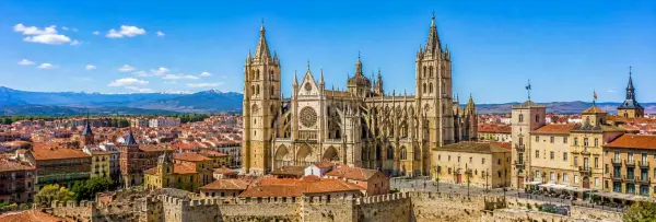 Panoramic view of León, Spain, featuring its Gothic cathedral, historic rooftops, city walls and mountain backdrop