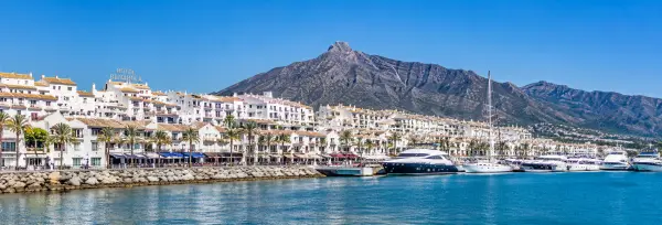 Marbella, Spain waterfront with white buildings, palm trees, yachts and Sierra Blanca mountains