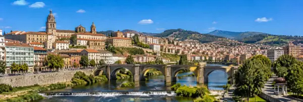 Panoramic view of Ourense, Spain, with the Miño River, historic bridge, cityscape and surrounding green hills