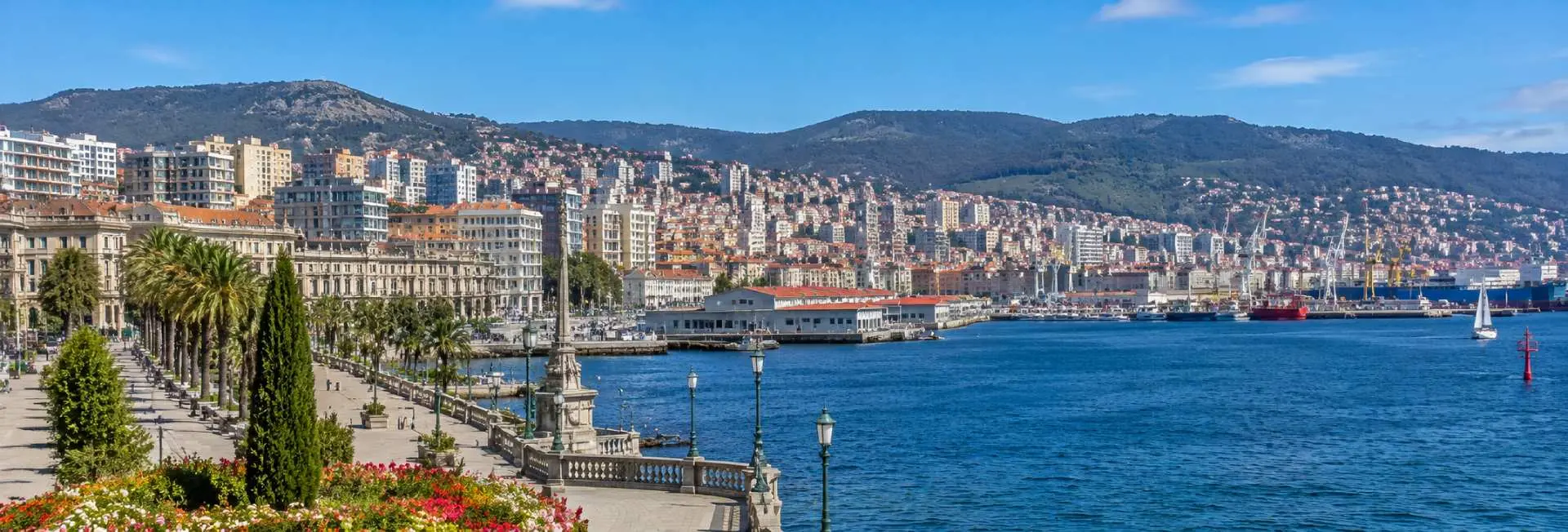 Vigo Spain waterfront with harbor, palm-lined promenade, hillside cityscape, and green mountains