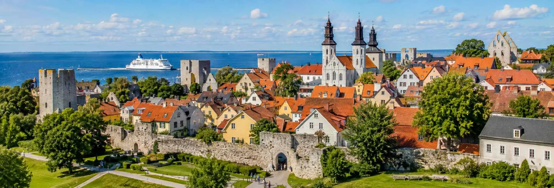 Visby, Sweden, with medieval stone walls, red-roofed houses, church ruins, and the Baltic Sea