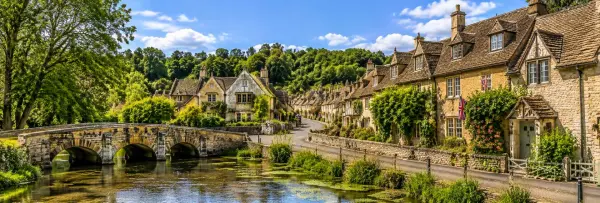 Honey-colored stone cottages and a historic bridge over a stream in the Cotswolds, UK