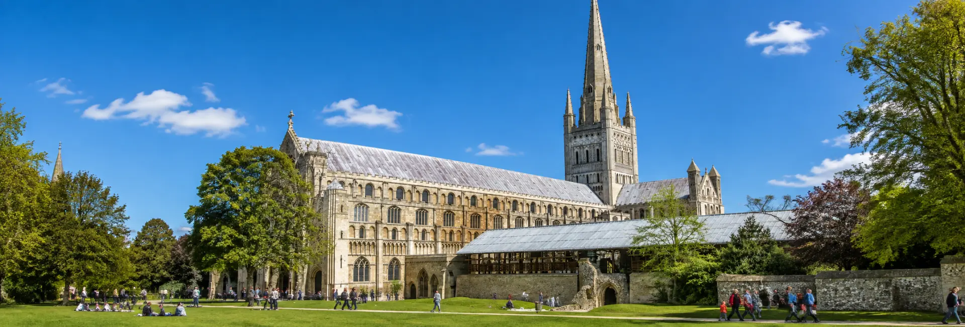 Norwich Cathedral and its historic grounds under a clear blue sky in Norwich, United Kingdom