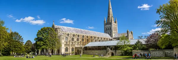 Norwich Cathedral and its historic grounds under a clear blue sky in Norwich, United Kingdom